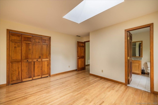 4665 Black Rock Tpke, Fairfield, CT 06824 - unfurnished bedroom with light wood finished floors, a skylight, baseboards, a closet, and ensuite bathroom