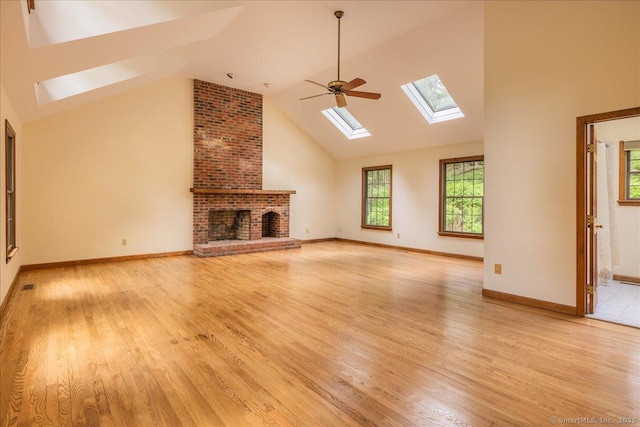 4665 Black Rock Tpke, Fairfield, CT 06824 - unfurnished living room with a skylight, light wood-style flooring, high vaulted ceiling, a brick fireplace, and baseboards