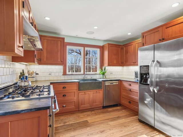 44 Meadow Ridge Dr, Easton, CT 06612 - kitchen featuring stainless steel appliances, under cabinet range hood, dark countertops, light wood finished floors, and brown cabinets