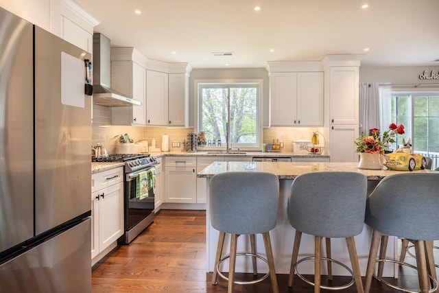 20 Jeffrey Ln, Southington, CT 06451 - kitchen with stainless steel appliances, wall chimney range hood, plenty of natural light, a kitchen bar, and recessed lighting