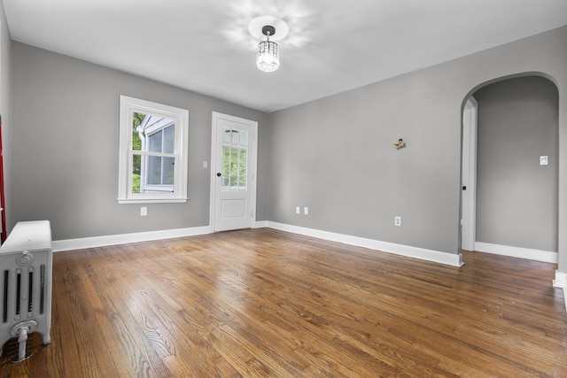 291 Maple Hill Rd, Naugatuck, CT 06770 - spare room featuring arched walkways, radiator, wood finished floors, and baseboards