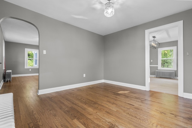 291 Maple Hill Rd, Naugatuck, CT 06770 - empty room featuring radiator, arched walkways, a chandelier, and healthy amount of natural light