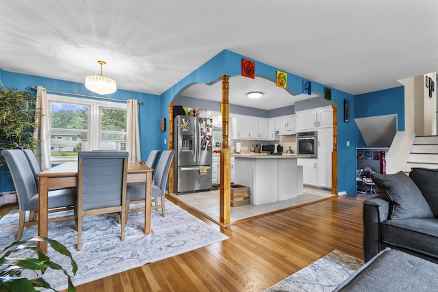 21 Cadwell Rd, Bloomfield, CT 06002 - dining space featuring light wood-style flooring, a chandelier, arched walkways, and stairs