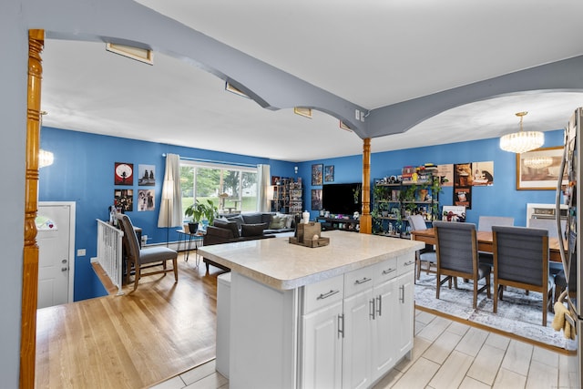 21 Cadwell Rd, Bloomfield, CT 06002 - kitchen featuring light countertops, arched walkways, white cabinets, and light wood-style floors