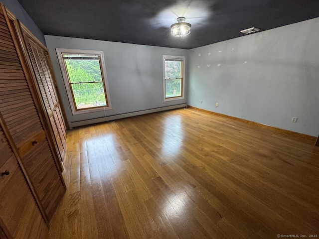 48 Bailey St, Trumbull, CT 06611 - unfurnished bedroom featuring a baseboard heating unit, multiple windows, light wood finished floors, and baseboards