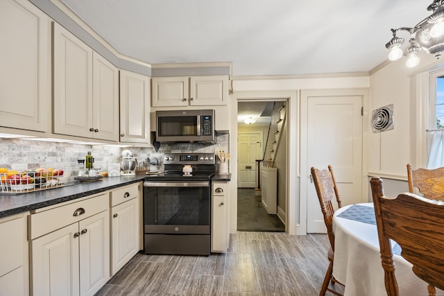 8 Usher Ave, Plainville, CT 06062 - kitchen with stainless steel appliances, light wood finished floors, backsplash, and dark countertops