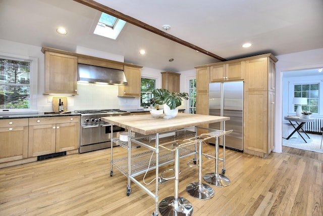 481 Ridgefield Rd, Wilton, CT 06897 - kitchen with appliances with stainless steel finishes, wall chimney range hood, tasteful backsplash, a skylight, and light wood-style floors