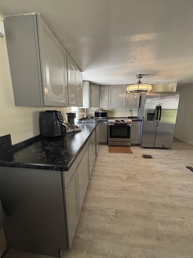 1012 Old Colony Rd Lot 85, Meriden, CT 06451 - kitchen featuring stainless steel appliances, dark countertops, light wood finished floors, a textured ceiling, and a sink