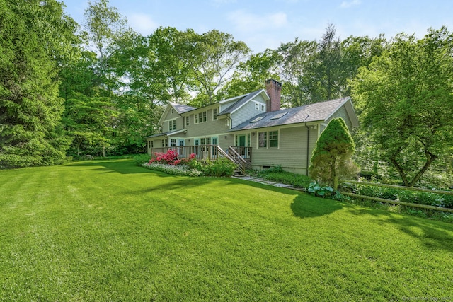 66 Saunders Dr, Wilton, CT 06897 - rear view of house featuring a lawn, a deck, a shingled roof, and a chimney