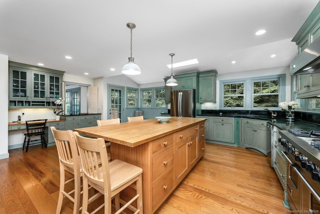 66 Saunders Dr, Wilton, CT 06897 - kitchen featuring stainless steel appliances, wood counters, light wood finished floors, a kitchen bar, and a center island