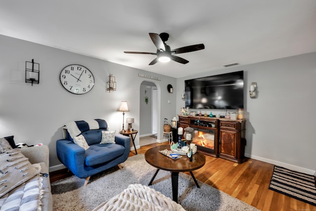 314 Old Wolcott Rd, Bristol, CT 06010 - living room featuring arched walkways, a ceiling fan, a glass covered fireplace, baseboards, and wood finished floors