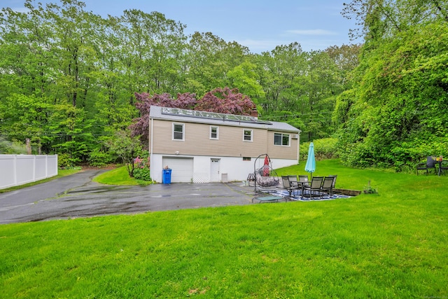 314 Old Wolcott Rd, Bristol, CT 06010 - rear view of property featuring asphalt driveway, a garage, a view of trees, a patio area, and a chimney