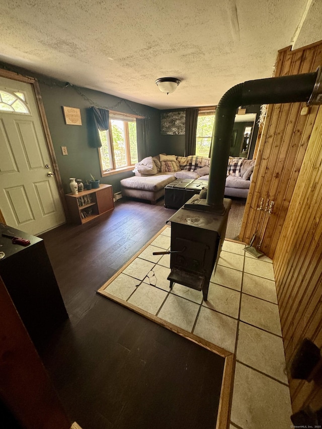 616 Crystal Lake Rd, Tolland, CT 06084 - living area featuring a textured ceiling, a wood stove, a baseboard heating unit, wooden walls, and wood finished floors