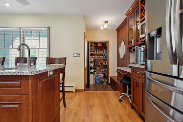 10 Colonial Dr, Clinton, CT 06413 - kitchen featuring stainless steel appliances, a baseboard heating unit, light wood-type flooring, a breakfast bar area, and glass insert cabinets