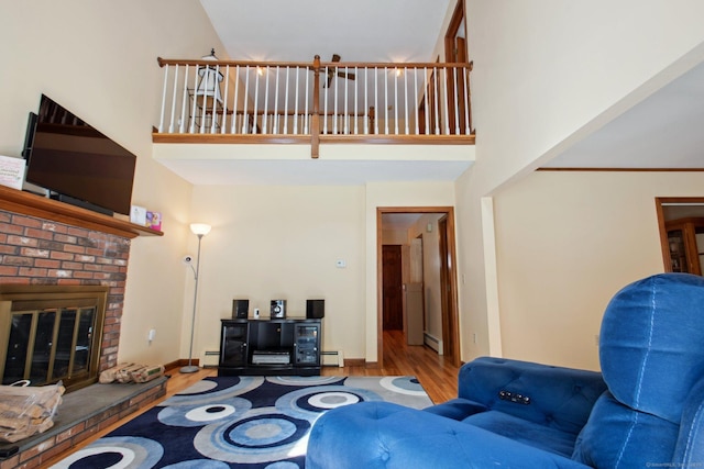 10 Colonial Dr, Clinton, CT 06413 - living room with wood finished floors, a towering ceiling, a brick fireplace, and a baseboard radiator