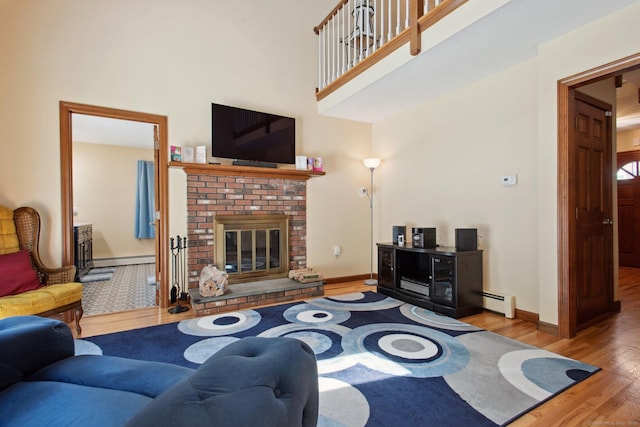 10 Colonial Dr, Clinton, CT 06413 - living area featuring a baseboard heating unit, wood finished floors, a towering ceiling, a fireplace, and baseboards