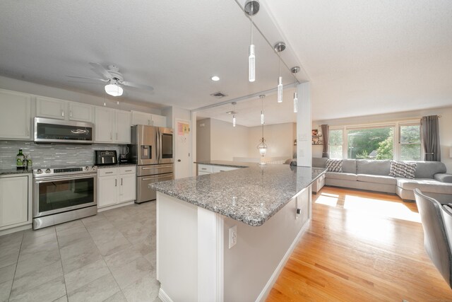56 Buena Vista Dr, East Hartford, CT 06118 - kitchen featuring appliances with stainless steel finishes, open floor plan, tasteful backsplash, light stone counters, and ceiling fan