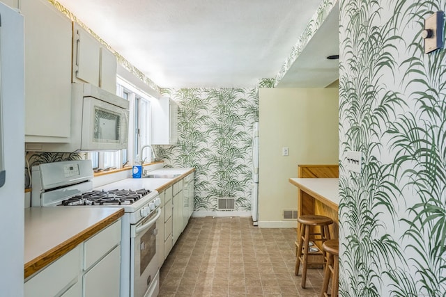 200 Willow St, Hamden, CT 06518 - kitchen with wallpapered walls, white appliances, baseboards, a sink, and light countertops