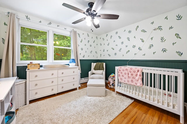 55 Andrasko Rd, Beacon Falls, CT 06403 - bedroom featuring wainscoting, wallpapered walls, a baseboard heating unit, wood finished floors, and a nursery area