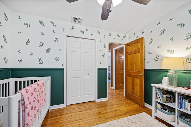 55 Andrasko Rd, Beacon Falls, CT 06403 - bedroom with wainscoting, a closet, wood finished floors, wallpapered walls, and a nursery area