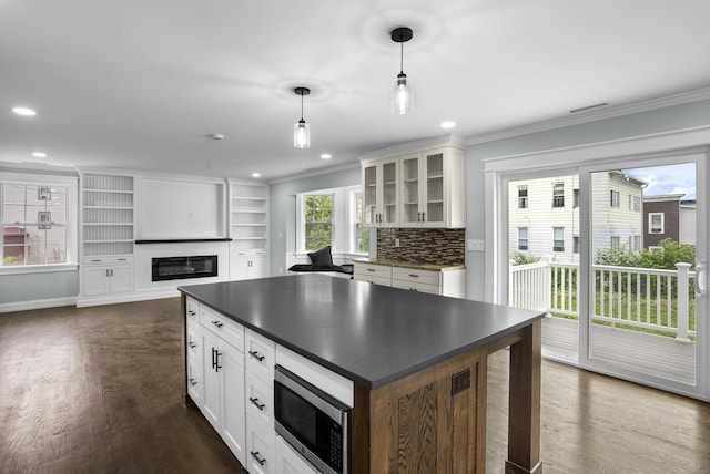 864 Baldwin St, Waterbury, CT 06706 - kitchen with stainless steel microwave, dark countertops, ornamental molding, dark wood-style floors, and glass insert cabinets