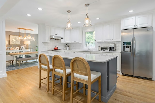 6 Queens Ln, Darien, CT 06820 - kitchen featuring stainless steel fridge, under cabinet range hood, light countertops, tasteful backsplash, and recessed lighting