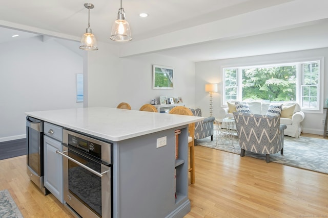 6 Queens Ln, Darien, CT 06820 - kitchen with gray cabinets, oven, light countertops, light wood-type flooring, and a center island