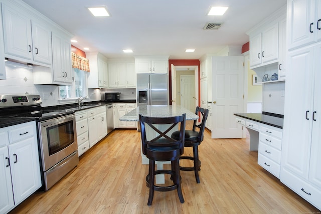 41 Blue Ridge Dr, Simsbury, CT 06089 - kitchen featuring stainless steel appliances, white cabinetry, light wood-style flooring, decorative backsplash, and a center island