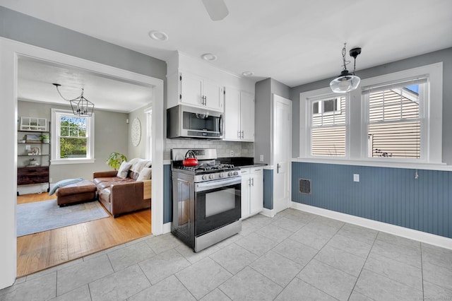 70 Mercer St, Stratford, CT 06614 - kitchen featuring appliances with stainless steel finishes, white cabinetry, light tile patterned floors, decorative backsplash, and decorative light fixtures