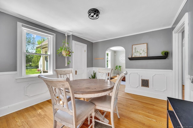 70 Mercer St, Stratford, CT 06614 - dining room featuring arched walkways, plenty of natural light, wainscoting, light wood-type flooring, and ornamental molding