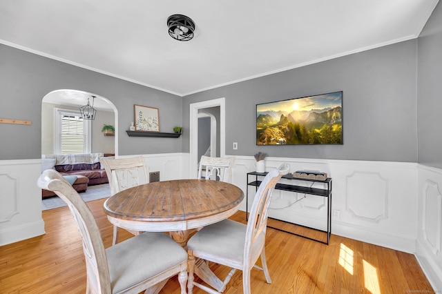 70 Mercer St, Stratford, CT 06614 - dining area featuring arched walkways, wainscoting, light wood-style floors, crown molding, and a decorative wall