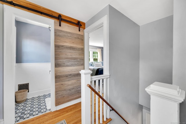 70 Mercer St, Stratford, CT 06614 - hallway with an upstairs landing, a barn door, wood walls, and wood finished floors