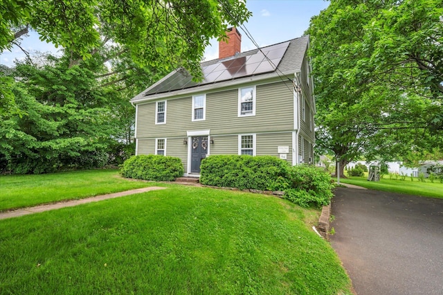 64 W St, Cromwell, CT 06416 - view of front of property with a chimney, solar panels, and a front lawn