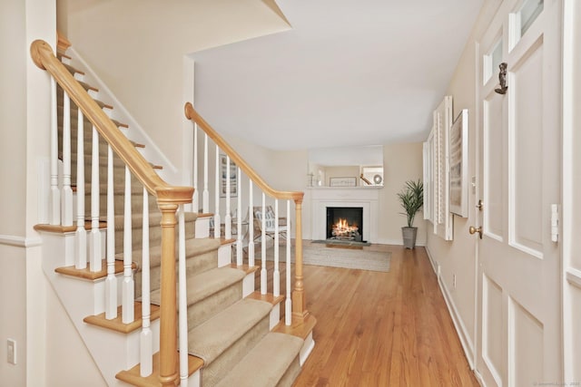 102 Pratt St, Fairfield, CT 06824 - entrance foyer with a lit fireplace, wood finished floors, stairway, and baseboards