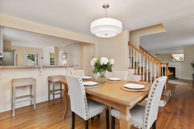 102 Pratt St, Fairfield, CT 06824 - dining space featuring light wood finished floors, stairway, a lit fireplace, and baseboards
