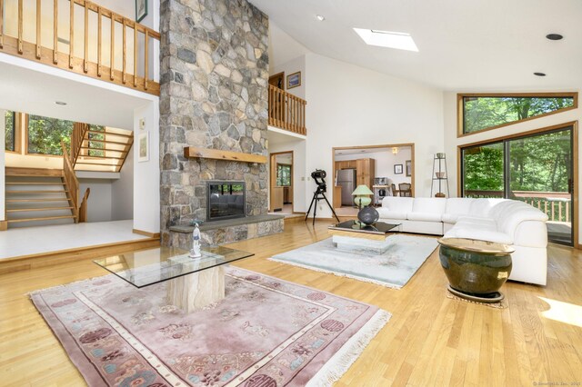 17 Walker Ln, Weston, CT 06883 - living room featuring high vaulted ceiling, stairway, a stone fireplace, wood finished floors, and a skylight