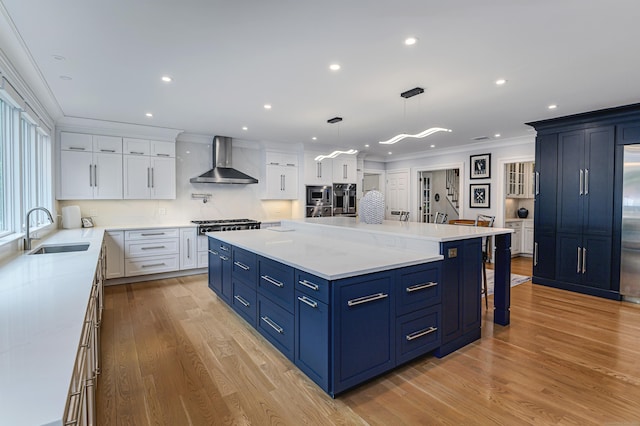 368 Nod Hill Rd, Wilton, CT 06897 - kitchen with wall chimney exhaust hood, a sink, crown molding, white cabinets, and light wood-type flooring