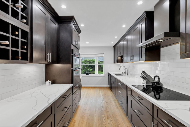 2 Quanaduck Cove Ct Unit 2, Stonington, CT 06378 - kitchen with wall chimney range hood, black electric cooktop, light wood finished floors, a sink, and light stone counters