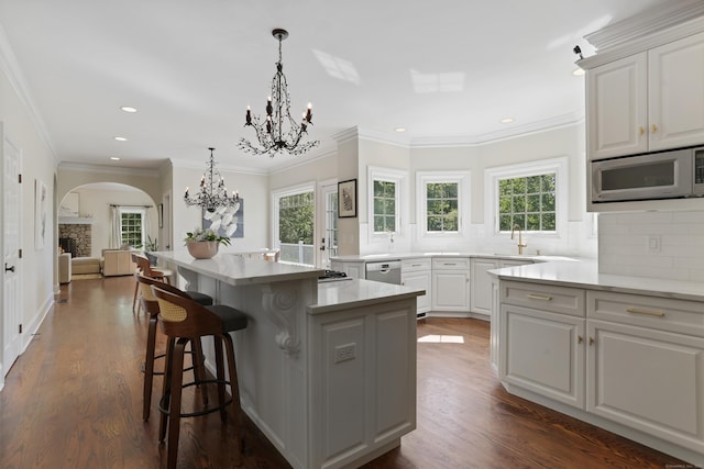 10 Easton Heights Ln, Easton, CT 06612 - kitchen featuring arched walkways, a chandelier, backsplash, white cabinetry, and a kitchen breakfast bar
