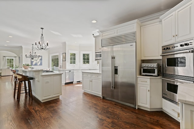 10 Easton Heights Ln, Easton, CT 06612 - kitchen featuring built in appliances, a chandelier, crown molding, recessed lighting, and arched walkways