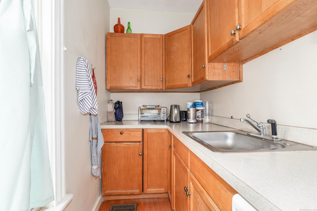 76 Edwards St, New Haven, CT 06511 - kitchen with light countertops, a sink, light wood finished floors, brown cabinets, and baseboards