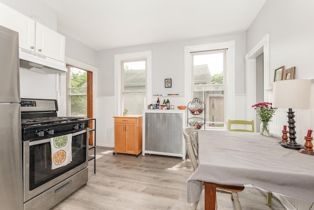 76 Edwards St, New Haven, CT 06511 - kitchen featuring stainless steel appliances, under cabinet range hood, a wainscoted wall, light wood-style flooring, and light countertops