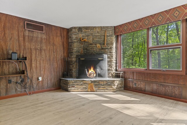 1 Indian Spring Ln, Norwich, CT 06360 - unfurnished living room featuring wood walls, a stone fireplace, wood finished floors, and baseboards