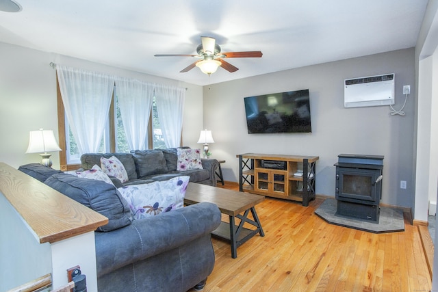 69 Fernwood Dr, Simsbury, CT 06070 - living room featuring a wood stove, a ceiling fan, a wall unit AC, and light wood-type flooring