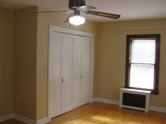 1071 River Blvd, Suffield, CT 06078 - unfurnished bedroom with radiator, light wood-type flooring, a closet, baseboards, and ceiling fan