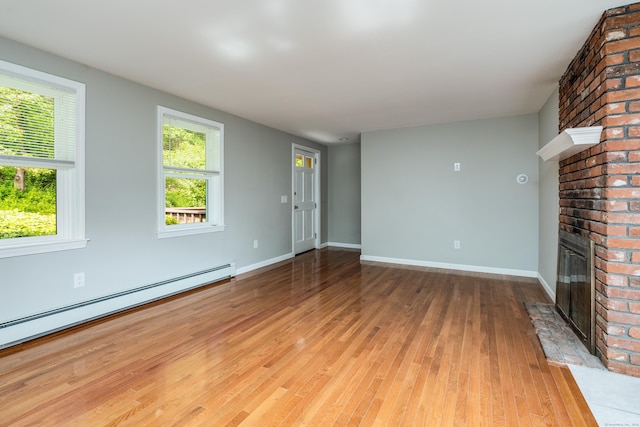 143 Clark Hill Rd, East Haddam, CT 06423 - unfurnished living room featuring a baseboard heating unit, a fireplace, light wood finished floors, and baseboards