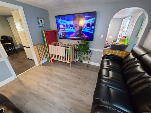 1437 Silver Ln, East Hartford, CT 06118 - living room featuring arched walkways, baseboards, and wood finished floors