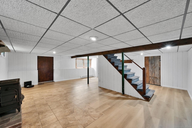 2 Broken Arrow Dr, East Granby, CT 06026 - below grade area with wood finished floors, a wood stove, stairs, a baseboard heating unit, and baseboards