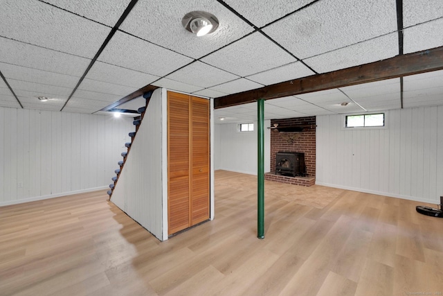 2 Broken Arrow Dr, East Granby, CT 06026 - basement with wood finished floors, a paneled ceiling, a wood stove, stairway, and baseboards