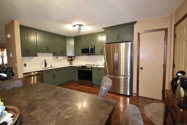 143 Pine Hill Rd Unit 8B, Thomaston, CT 06787 - kitchen with appliances with stainless steel finishes, green cabinetry, a sink, dark wood-style floors, and a textured ceiling